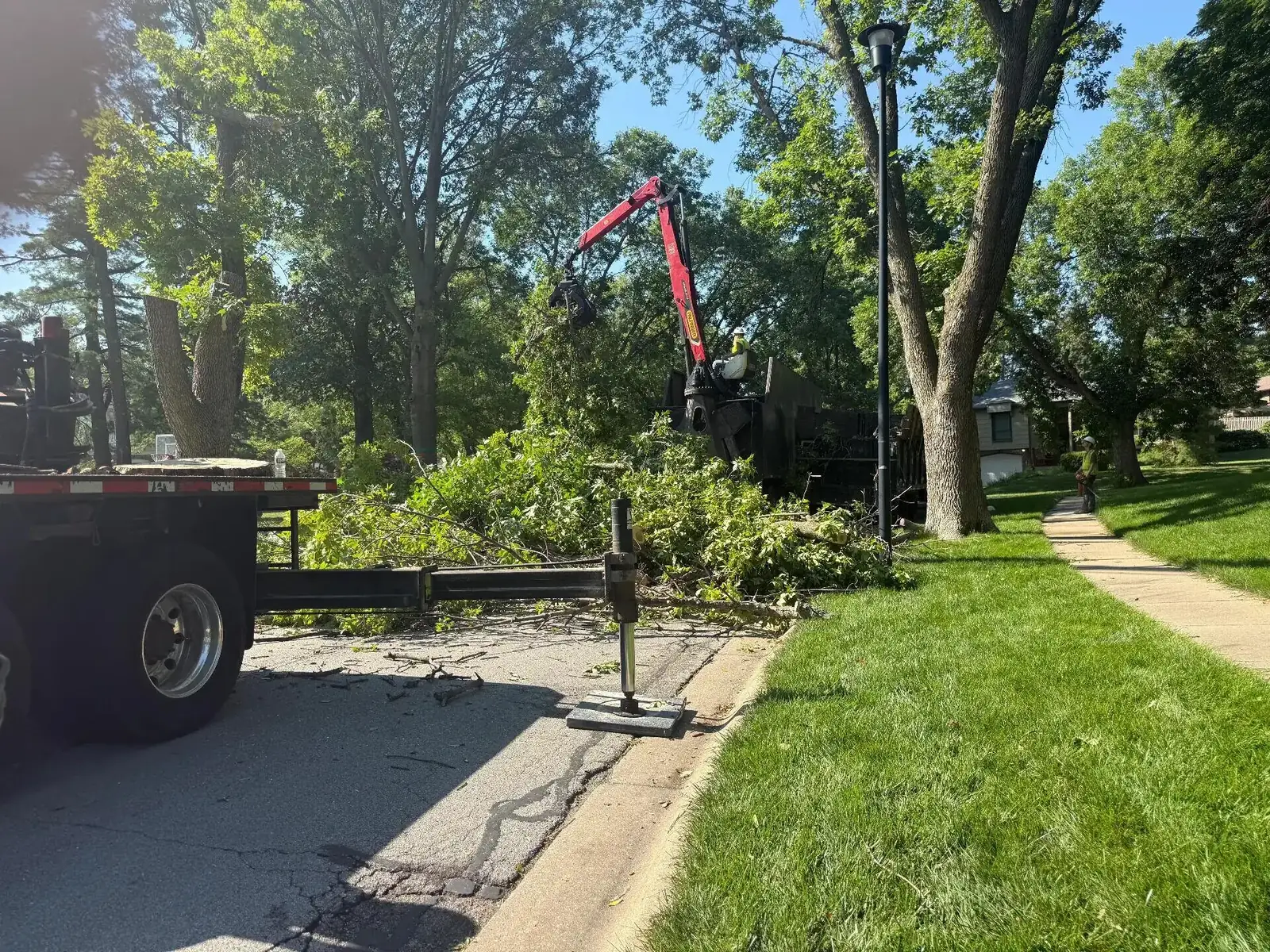 Crane lifting a whole oak tree section over a house roof in Jonesboro AR